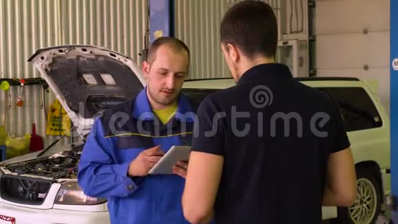 汽车机械师在车库里使用平板电脑进行发动机诊断车视频的预览图