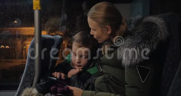 孩子和妈妈在公共汽车上用手机视频的预览图
