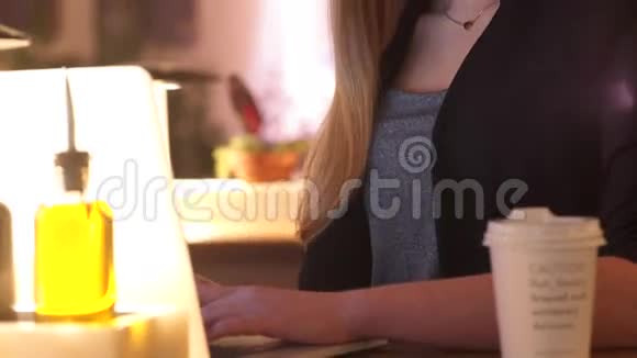 穿着黑色夹克的微笑的年轻女孩坐在咖啡馆A里她用笔记本专注于工作视频的预览图