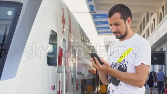 一个年轻人在火车站用智能手机视频的预览图