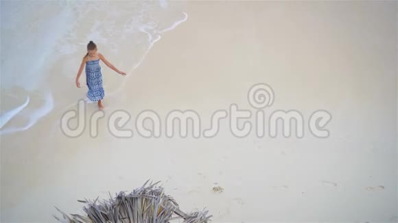 可爱的小女孩在浅水里玩得很开心从上面看到一片荒凉的海滩上面有绿松石水视频的预览图