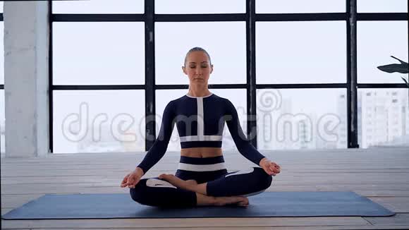 一个美丽的年轻女子在手泥拉和命名瑜伽姿势冥想室内的肖像个人运动体育运动视频的预览图