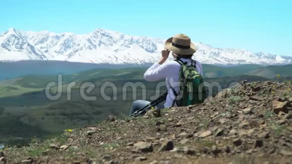 旅行者的女人坐在山上看雪山视频的预览图