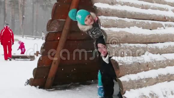 在冬天的公园里下雪时快乐的母女从木屋里往外看视频的预览图