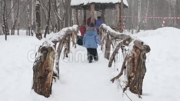 冬天公园下雪的时候两个小男孩和小女孩在桥上玩耍视频的预览图