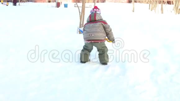 快乐的小男孩在冬天的晴天挖铲雪视频的预览图