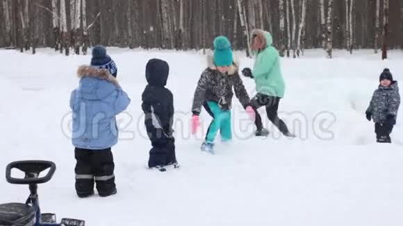 冬天公园下雪时女人和四个孩子玩雪球视频的预览图