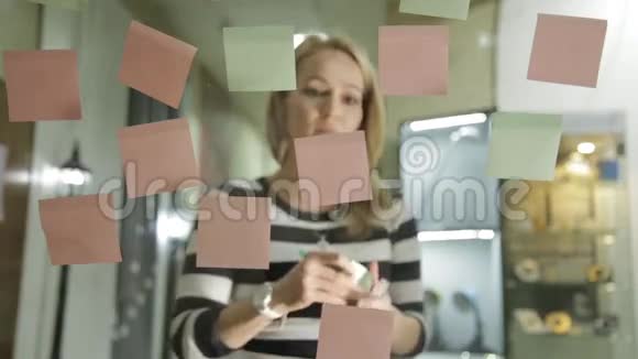 创意女商人准备在现代玻璃办公室进行头脑风暴使用不同颜色的贴纸视频的预览图