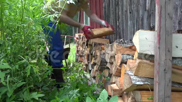 人在村里的房子墙附近卸下整齐的木头4K视频的预览图