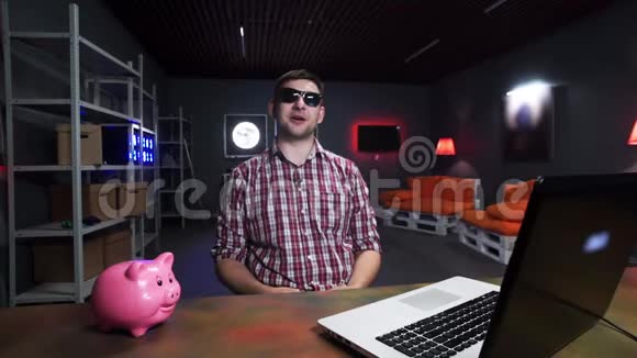 戴墨镜的帅哥在镜头前讲话有猪和笔记本电脑视频的预览图