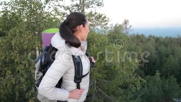 日出时带背包在山顶欣赏山谷景色的女徒步旅行者视频的预览图