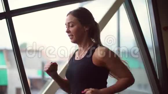 20多岁的运动女性在健身房特写镜头前的跑步机上跑步视频的预览图