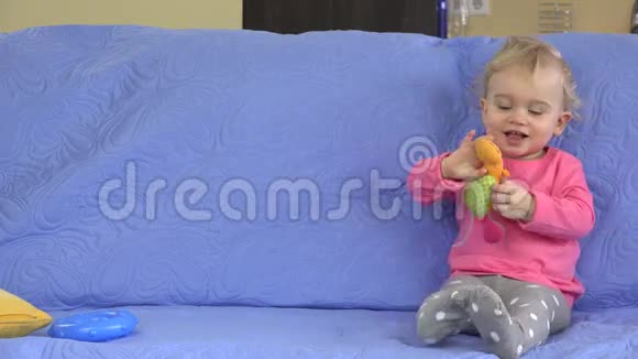 有趣的快乐蹒跚学步的女孩在沙发上玩她的玩具视频的预览图