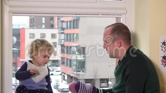 父亲带着女儿带着帽子出去了雪花飘落的窗户视频的预览图