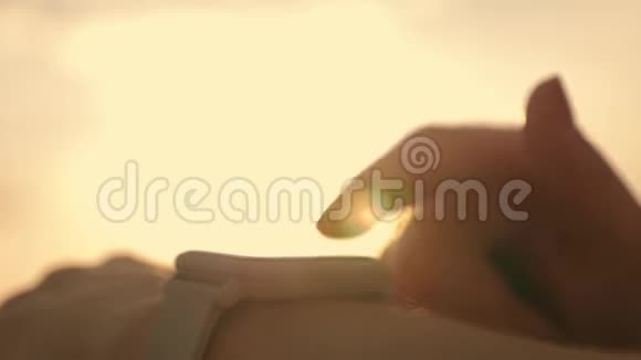 日落时一个在田野里的女孩看着一个智能时钟傍晚在日落时分用智能跑步视频的预览图