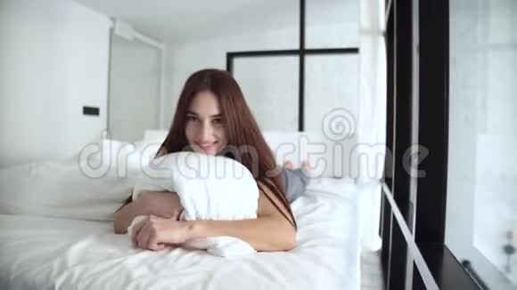 美丽的女人躺在舒适的床上拥抱枕头视频的预览图