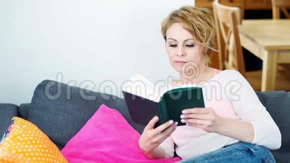 坐在灰色沙发上看书的女人视频的预览图