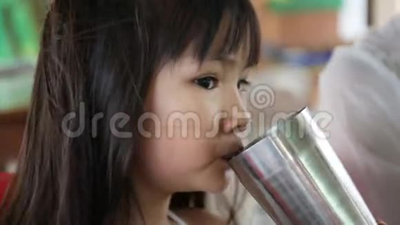 年轻的亚洲孩子喝一杯水视频的预览图