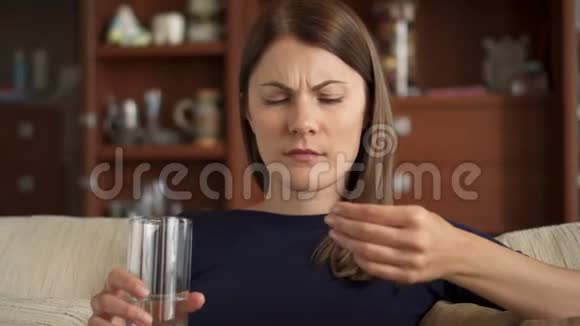 年轻女子在家吃药生病和生病头痛有药片和水视频的预览图