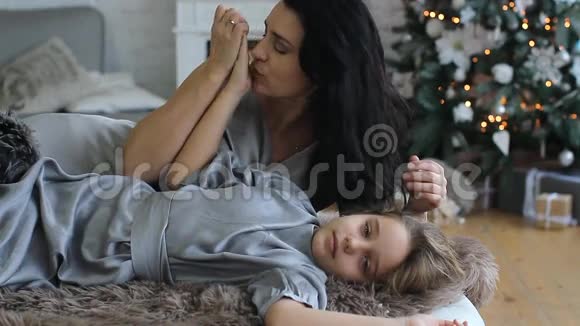 妈妈和女儿在他家的圣诞树背景下休息视频的预览图