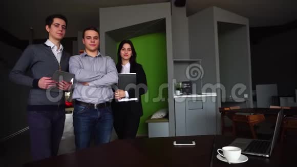 三个自信的男孩女孩学生或员工站在办公室微笑着看着相机视频的预览图