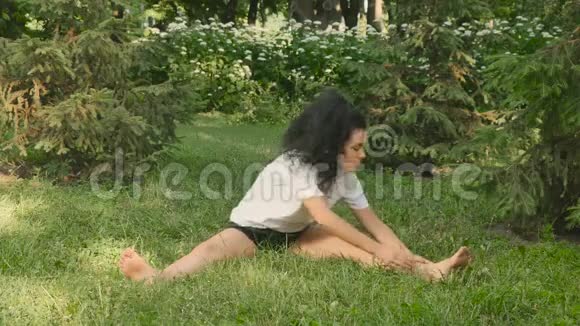 运动女子在公园的草地上做伸展运动视频的预览图