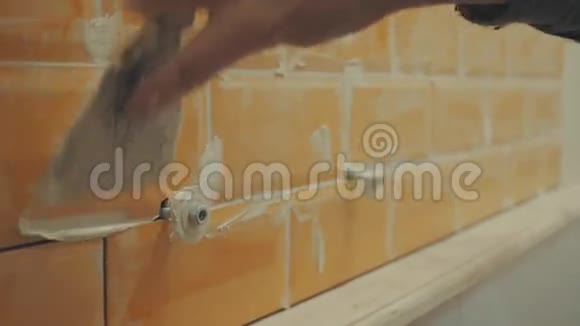 人用手在墙上贴上橙色瓷砖的接缝视频的预览图