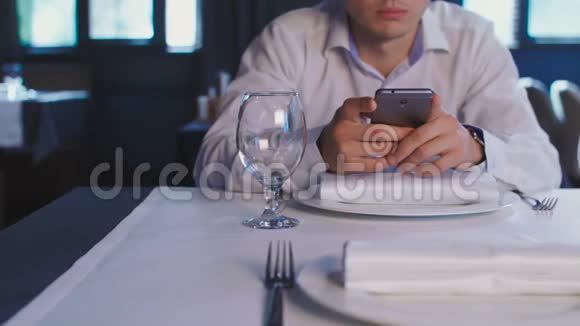 年轻人在餐厅的餐桌上等待点餐时使用智能手机视频的预览图