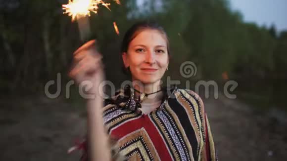 在海滩派对上带着火花的年轻微笑女人的肖像视频的预览图