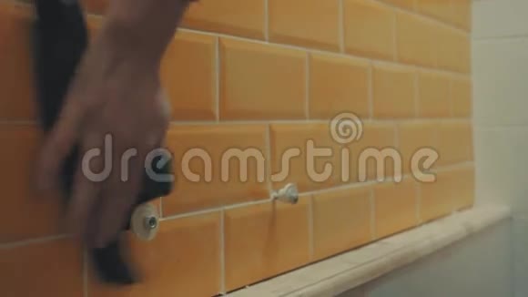 男的手把墙上橘色瓷砖上的残余腻子洗掉了视频的预览图