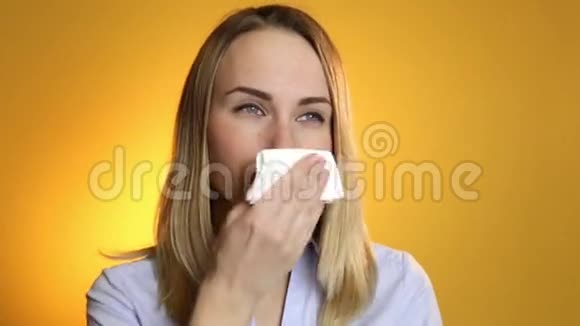 生病的女人把他的鼻子吹成黄色背景的组织视频的预览图