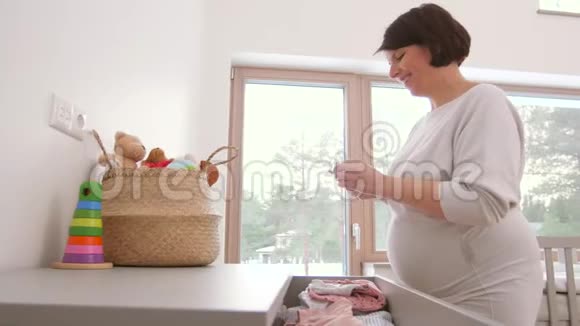 快乐的孕妇在家里套婴儿衣服视频的预览图