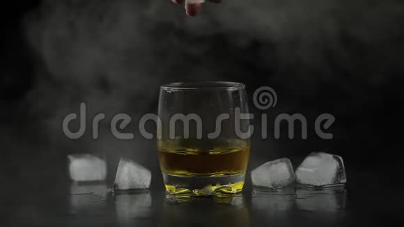 威士忌加冰在黑色背景下从瓶子里倒入威士忌朗姆酒视频的预览图