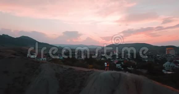 山峰日落海和城市山谷边缘的史诗岩石和太阳耀斑4k无人驾驶飞机视频的预览图