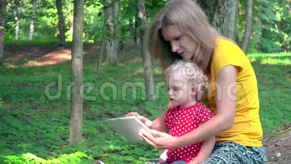 保姆和可爱的女婴在公园里使用平板电脑视频的预览图