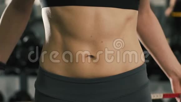 一个漂亮的女孩在健身房用测量带检查她的腰部视频的预览图