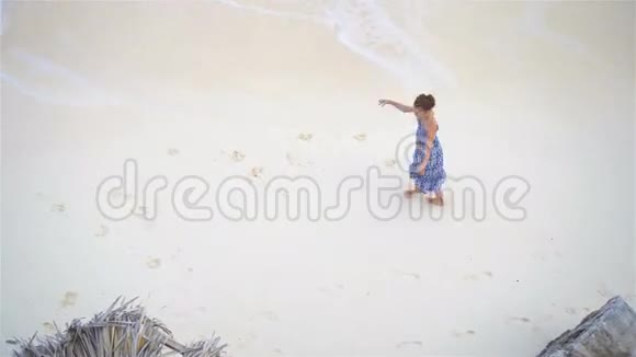 可爱的小女孩在浅水里玩得很开心从上面看到一片荒凉的海滩上面有绿松石水视频的预览图