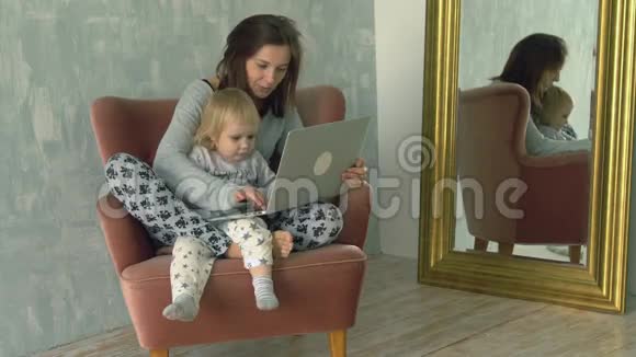 一个漂亮的女人用笔记本电脑膝盖上有个小宝宝视频的预览图