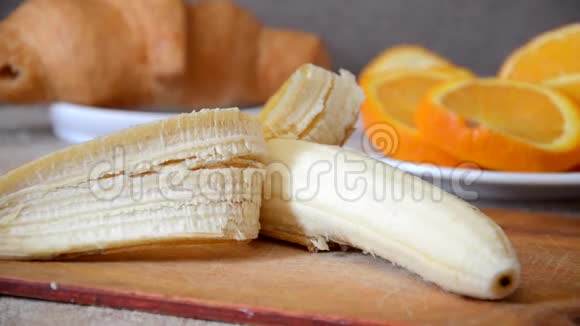 一片片香蕉砧板用刀切背景切片橙色和牛角面包视频的预览图