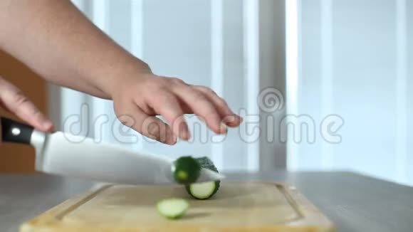厨刀的手大厨房一根新鲜的黄瓜放在一棵树上的砧板上视频的预览图