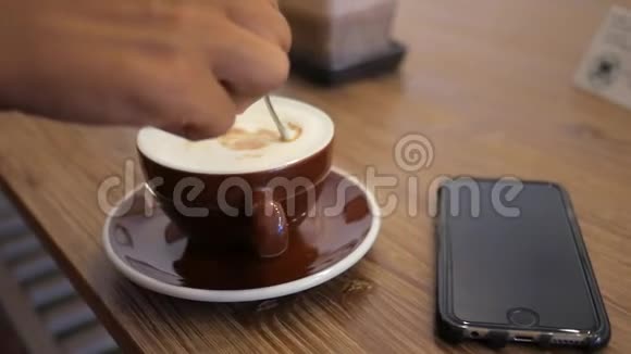 女用手在咖啡厅热咖啡杯中搅拌糖和豆浆高清慢速运动视频的预览图