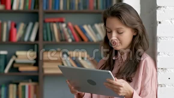 可爱的学生在图书馆里用平板电脑视频的预览图