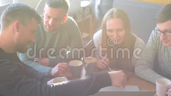 一群快乐的朋友或同事在一家小咖啡馆或小酒吧里聊天大笑和使用电脑视频的预览图