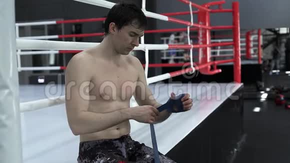 男拳击手在拳击训练前用蓝手包住他的手视频的预览图