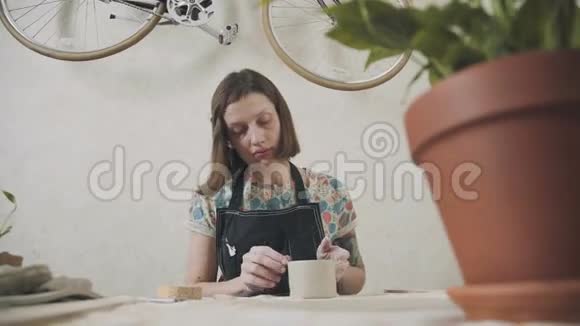 在她的艺术工作室里的女陶工从事制造粘土杯视频的预览图