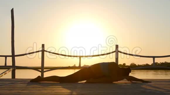 苗条的女人在橙色的阳光下做瑜伽视频的预览图
