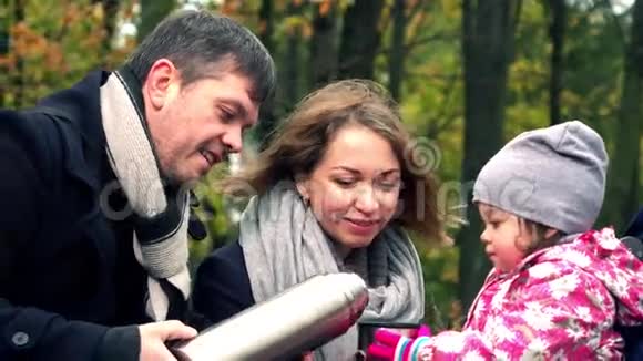 父母和他们的孩子在秋天公园休息喝金属真空瓶的茶4Ksteatam视频视频的预览图