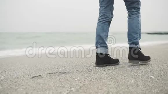一个年轻的时髦男人或女人穿着芥末裤和黑色时髦的鞋子独自在海滩上行走视频的预览图