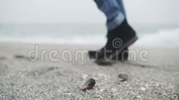 一个年轻的时髦男人或女人穿着芥末裤和黑色时髦的鞋子独自在海滩上行走视频的预览图