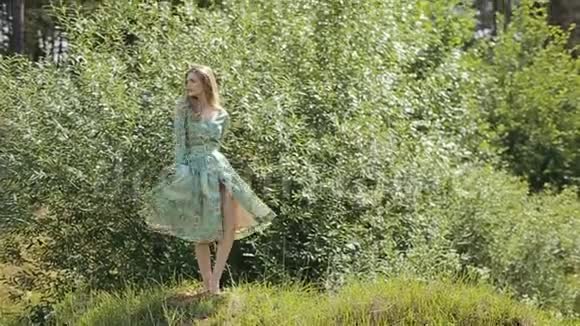 阳光明媚的夏日一个穿着长裙的年轻女孩在公园散步视频的预览图